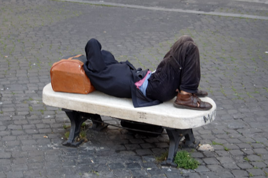 Sleeping man on a marble bench in Rome.